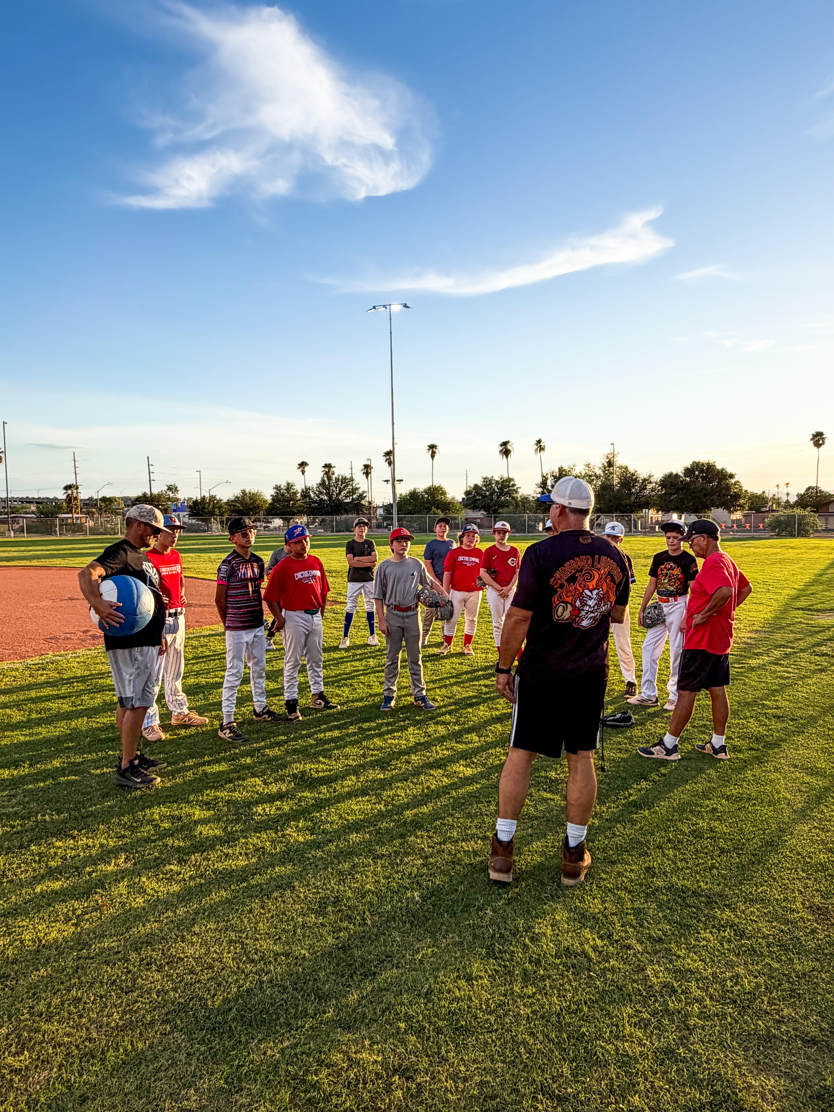 Coach addressing players in a circle at sunset practice