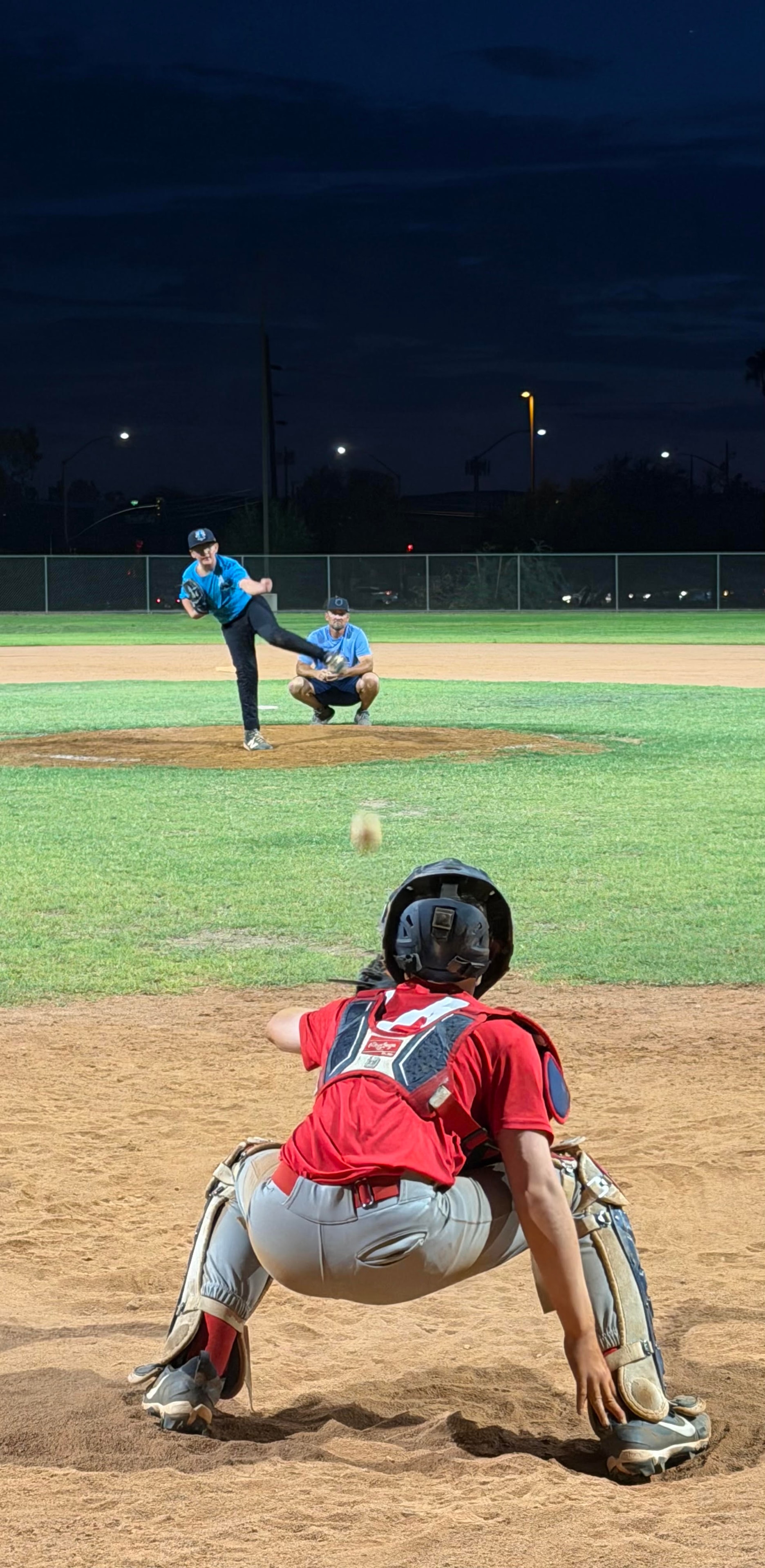 Pitcher delivering to catcher during a night practice