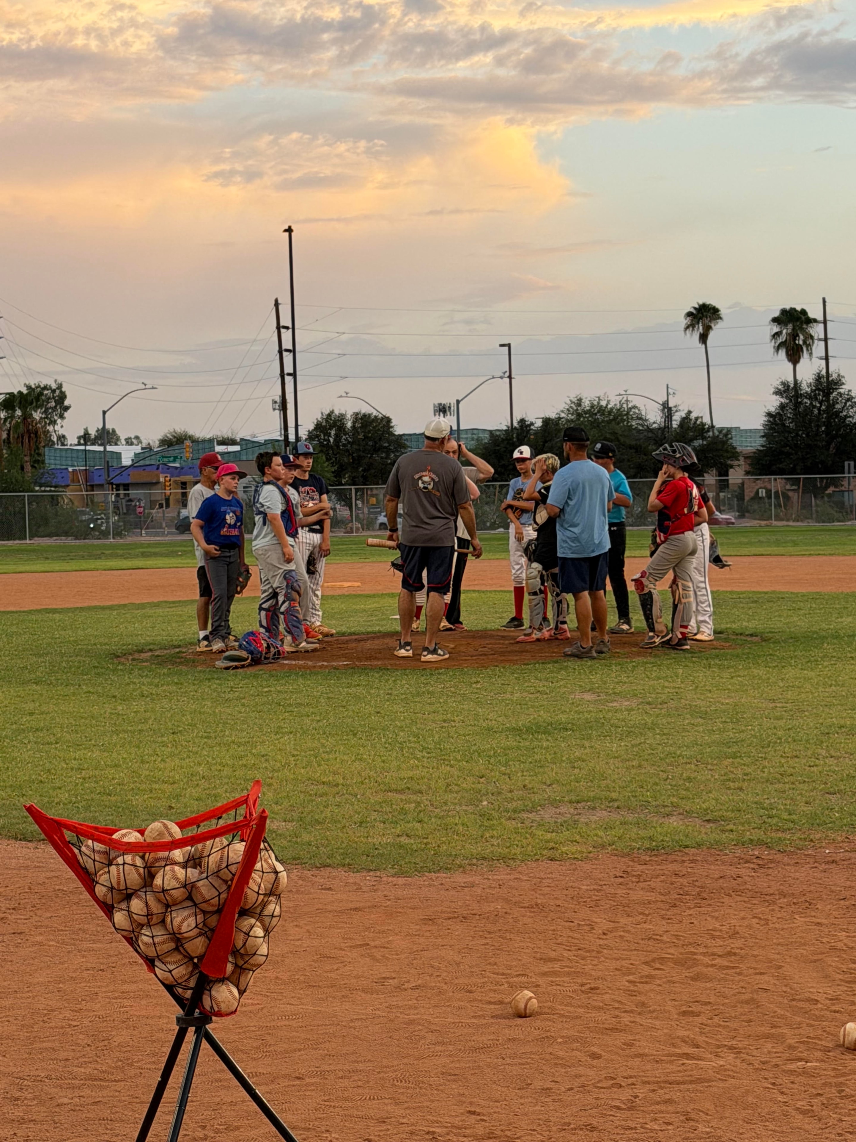 Wide shot of practice with ball bucket in foreground at sunset